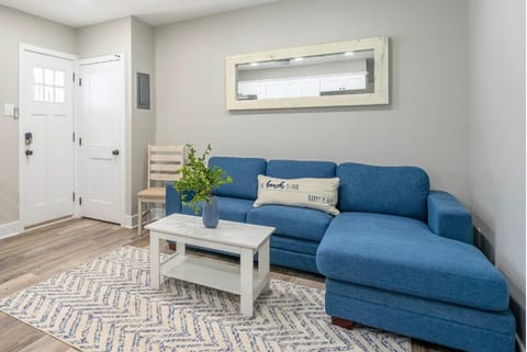 Bright and cozy living area with a comfortable sectional sofa, stylish decor, and a coffee table for relaxing. A perfect spot to unwind after a beach day, with natural light and a clean, modern coastal feel.