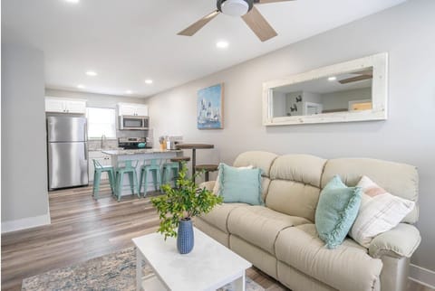 Relax in this open-concept living space featuring a comfy sofa, modern kitchen, and beachy touches throughout. Perfect for gathering, dining, or unwinding after a sunny day on the shore.