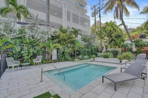 Small pool with sun loungers surrounded by lush tropical plants.
