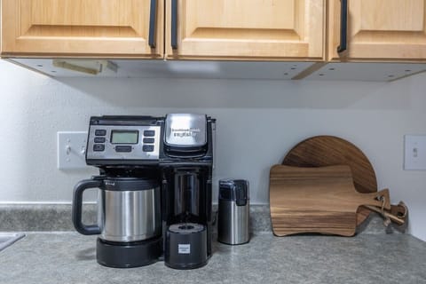 The sleek coffee maker stands ready, surrounded by a jar of rich, aromatic coffee beans