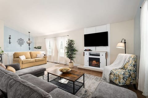 Gather around the modern fireplace in this bright living room, complete with cozy sofas and streaming-ready TV for relaxing evenings.