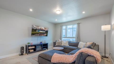 Spacious and bright living room featuring a large sectional sofa, smart TV, and soft lighting
