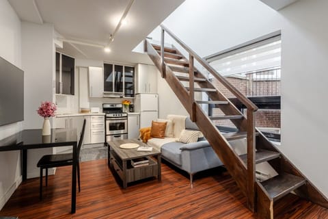Modern open-plan space with a sleek kitchen, cozy sectional, and stylish loft stairs