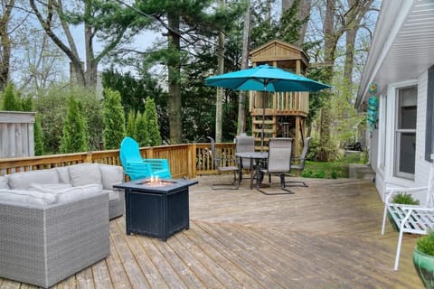 Backyard with mature trees, an expansive deck, and a wooden playhouse. Please note the playhouse is no longer available as of January 2026.