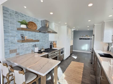 Coastal gourmet kitchen, completely remodeled in 2026 and equipped with chef-grade appliances, granite countertops, and custom cabinetry. Designed for both style and function, this bright and airy space is fully stocked with everything you need to prepare meals and entertain with ease. Pantry items not included.