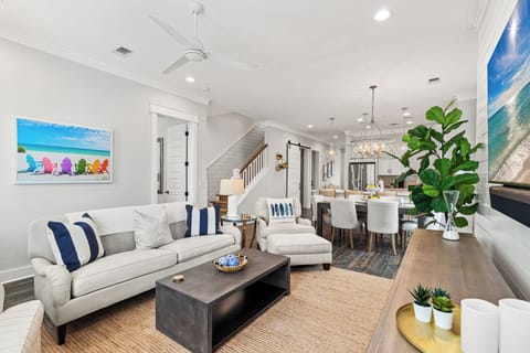 Relax in your bright, coastal-inspired living space with plush seating and ocean artwork setting the perfect beachside mood.
