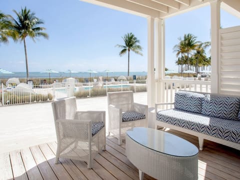 Cozy beachfront patio with elegant seating, offering breathtaking views of the ocean and swaying palms.