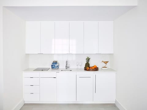 Sleek and functional kitchenette with bright white cabinetry, ideal for preparing light refreshments.