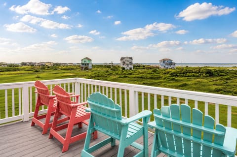 Spacious covered balcony with colorful Adirondack chairs overlooking coastal landscape—relaxing outdoor seating with Gulf breeze.