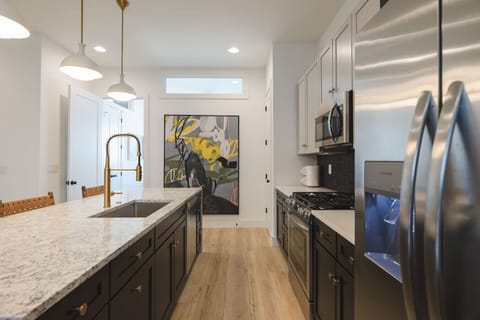 A modern kitchen with sleek stainless steel appliances, a spacious marble island, and stylish pendant lighting.