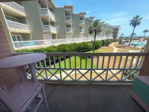 Private balcony with pool views, palm trees, and a peek of the ocean