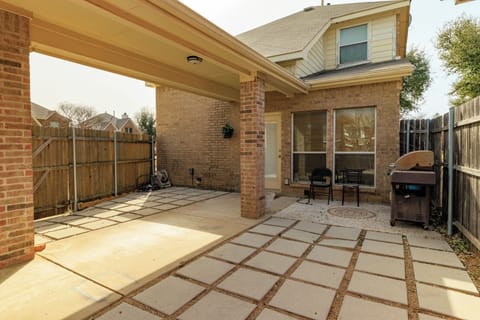 Fully fenced outdoor patio with chairs and grill.