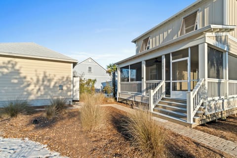 Beautiful coastal cottage with screened porch and charming walkway, surrounded by native landscaping in a peaceful beachside neighborhood.