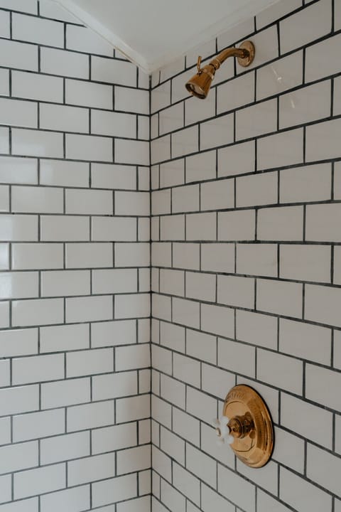 The Hemingway Room’s ensuite bathroom features a sleek subway-tiled rain shower, offering a refreshing and modern contrast to the room’s rustic charm.