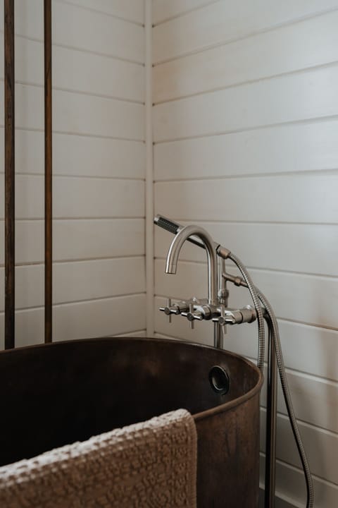 Elegant Vintage Bathtub Details – The gleaming brass fixtures and rich patina of the copper tub create a luxurious and inviting bath experience, perfect for a soothing soak.