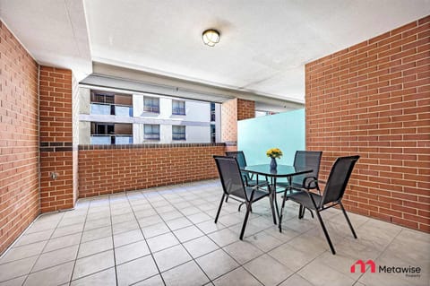 Private covered balcony with outdoor table and chairs, surrounded by brick walls.