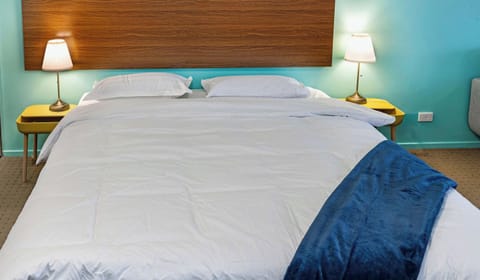 Close-up of the king-size bed with wooden headboard and bedside lighting.