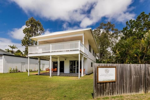 Two‑story coastal home with balcony, patio seating, and tropical garden surrounds. Family‑friendly setting close to Agnes Water Main Beach.