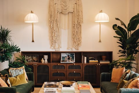 Inviting lounge with a vintage touch, featuring rich textures, lush greenery, and soft lighting for a cozy, intimate ambiance.