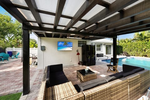 This gourmet-style setup includes a built-in BBQ grill, ample counter space, and storage, making meal preparation effortless. The covered design allows for year-round use, while comfortable seating, ambient lighting, and stylish decor create an inviting atmosphere.