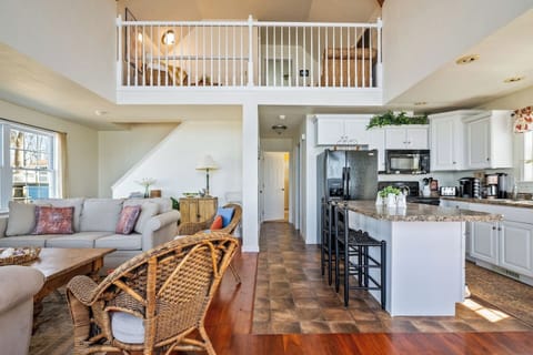 Step into a bright and inviting open-concept living space with soaring vaulted ceilings, a charming loft, and a cozy blend of modern and rustic decor. The warm wood tones, wicker accents, and comfortable seating make it the perfect retreat for relaxa
