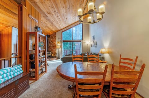 Bright open living area with vaulted ceilings and pine tree forest view.