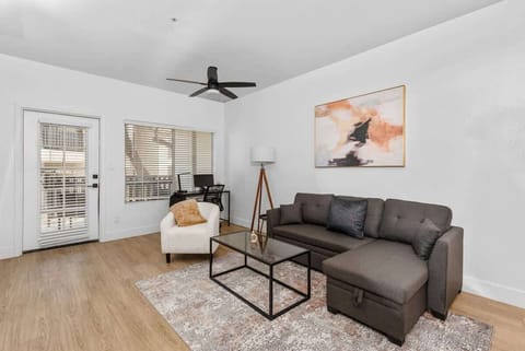 Modern living room with accent wall, dedicated working space, TV, plush couch, and sofa bed