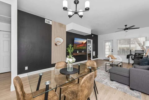 Dining area, seats 4, high chair Modern living room with accent wall, dedicated working space, TV, plush couch, and sofa bed