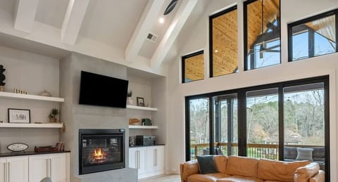 Sunlit haven with soaring ceilings, plentiful natural light, 55` LG WebOs TV, and a warm fireplace, perfect for relaxing evenings!