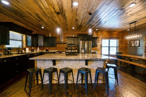 Rustic charm meets modern amenities in this cozy cabin kitchen, complete with a stone island bar and sleek appliances.
