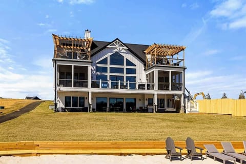 Elegant Lakefront Home: A breathtaking three-story retreat featuring expansive windows, multiple balconies with pergolas, and seamless indoor-outdoor living, all overlooking a private sandy beach and Lake Anna.