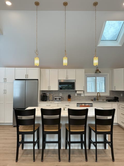 Bright kitchen with 12' ceilings and an island with 4 chairs.
