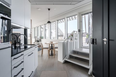 Modern, fully equipped kitchenette and hallway with sleek black and white finishes.