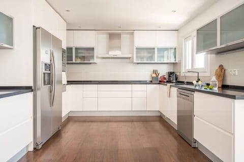 Discover your inner chef in this modern, well-equipped kitchen. With a spacious countertop, a large refrigerator, and all the essential appliances, preparing meals for a large group has never been easier.