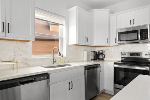 - Modern kitchen features quartz counters, white cabinetry, & a herringbone backsplash
- Stainless appliances, a sink, & coffee station make mornings a breeze
- Whether prepping meals or sipping coffee, you'll love the function & flow of this space