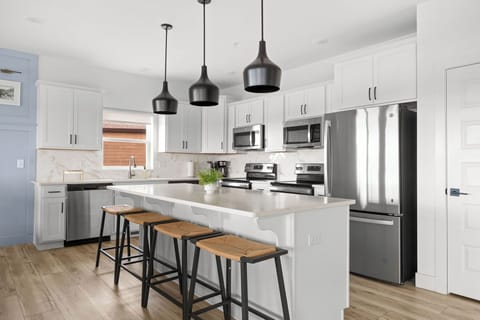 - Whip up meals in this kitchen with black pendant lights & sleek countertops
- Fully equipped with stainless steel appliances including double ovens & a large fridge
- Island seating for four makes it perfect for breakfast chats or evening cocktails