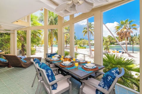Screened atrium with patio dining table and waterfront views. 