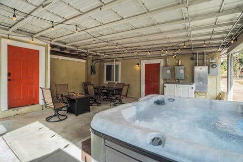 Enjoy the large, bubbling hot tub located on the covered concrete patio. This outdoor space also features a dining table with chairs, a small fire pit table, and string lights overhead. Please note that this area is shared with other units