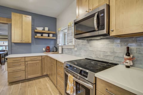 A fully equipped kitchen for effortless meal prep – featuring sleek countertops, stainless steel appliances, and open shelving for easy access to essentials. The stylish blue accent wall adds a modern touch to this inviting space.





