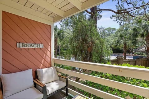 Charming balcony with comfy chairs, ocean view, and peaceful palm-filled vista.