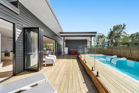 Private pool bordered by wooden deck, surrounded by sun loungers.