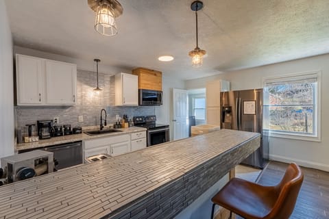 Full kitchen with dishwasher, fridge, microwave, toaster and eat-in bar