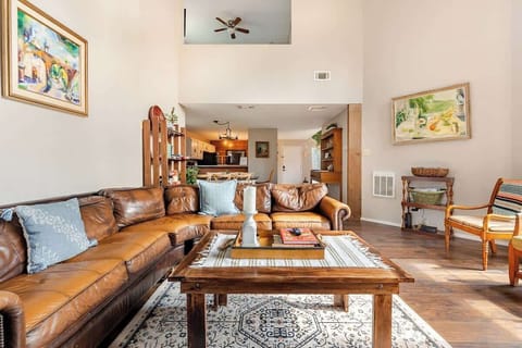 Unwind in this cozy, sunlit living room featuring soaring ceilings, a rustic stone fireplace, and an incredibly comfortable, plush leather sectional. Perfect for movie nights or morning coffee with scenic views through the floor-to-ceiling windows.