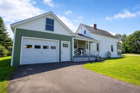 Charming farmhouse retreat with a spacious yard, covered porch, and attached garage for a comfortable country getaway.