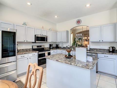 Modern kitchen with stainless steel appliances, white cabinetry, and a central island—perfect for preparing home-cooked meals during your stay.