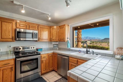 This fully equipped kitchen features stainless steel appliances, ample counter space, and a large window showcasing breathtaking red rock views.