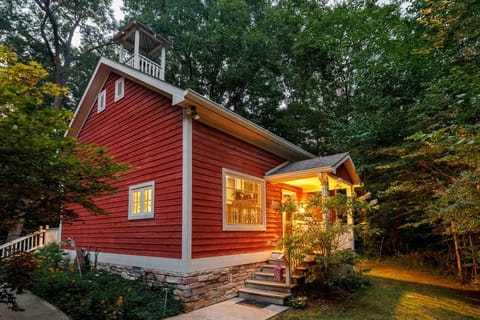 Historic 1891 schoolhouse beneath the trees with a warmly lit private entrance