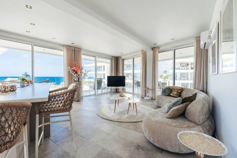 Bask in coastal luxury—this sun-drenched lounge boasts panoramic ocean views, soft curved seating, and chic woven textures, creating the perfect blend of comfort and elegance by the sea.