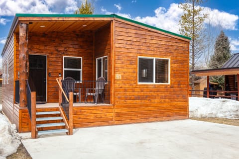 Chalet with a front balcony and parking space for two vehicles.