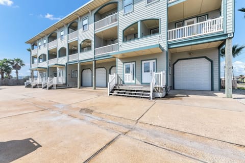 Coastal vacation rental with private garage and balcony access in a palm tree-lined setting.